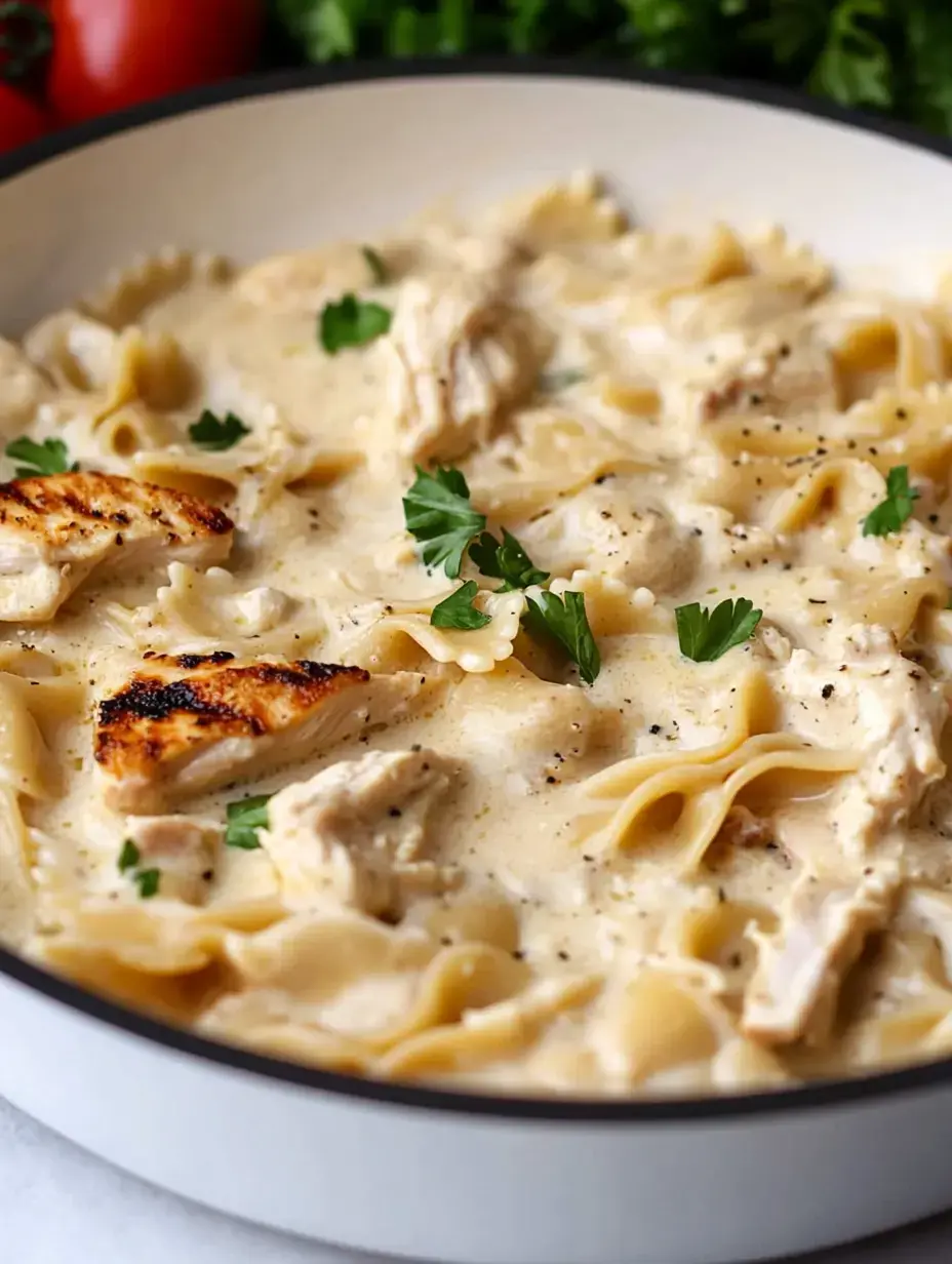 A creamy pasta dish featuring bowtie noodles, shredded chicken, and garnished with fresh parsley.