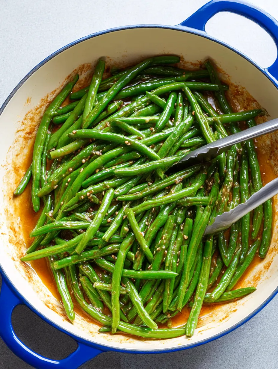 A bowl of green beans with seasoning.
