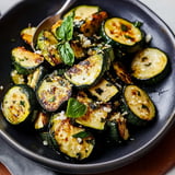 A bowl of sautéed zucchini slices garnished with fresh basil and sprinkled with Parmesan cheese.