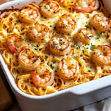 A baked dish of pasta topped with golden shrimp and sprinkled with parsley.