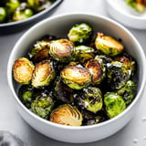 A bowl of crispy roasted Brussels sprouts garnished with salt.